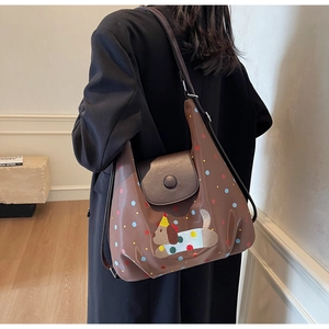 Detail of brown polka dot tote bag featuring cartoon dog embroidery on a female model