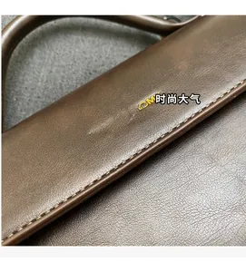 Close-up of deep brown lychee grain leather handbag with gold embossed logo