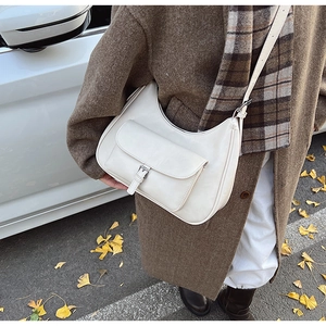 Detail of white half-moon crossbody bag with front pocket and silver metal buckle closure