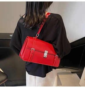 Détail d'un sac bandoulière rouge brillant avec plis accordéon et boucle argentée