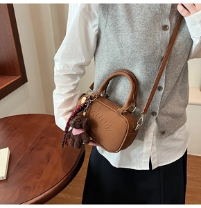 Detail of brown leather bowling bag with Audai Bear embossing and plush bear charm