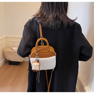 Brown suede mini handbag with white plush trim and cute toast charm shown on model