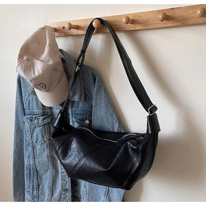 Detail of black crescent shoulder bag with vintage crinkled texture and silver buckle