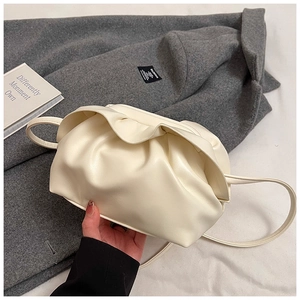 Détail du sac nuage blanc plissé avec fine bandoulière sur fond de manteau en laine grise