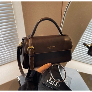 Detail of vintage brown leather handbag with gold hardware and embossed branding text