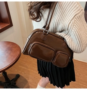 Dettaglio borsa a spalla marrone scuro lucida con tasche con zip in ambiente lifestyle