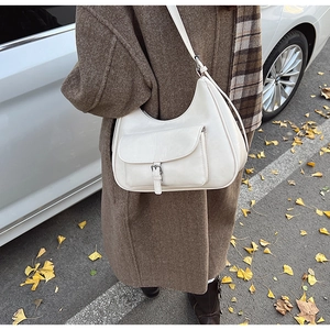Close-up of an off-white leather half-moon shoulder bag with a buckle flap pocket detail