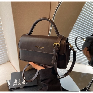 Detail of vintage dark brown faux leather bag with gold-tone logo and adjustable strap