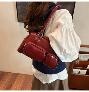 Dettaglio borsa a spalla in pelle lucida bordeaux con doppie tasche frontali con zip