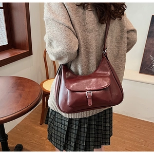 Detail of burgundy hobo bag with silver buckle pocket on a model in home interior