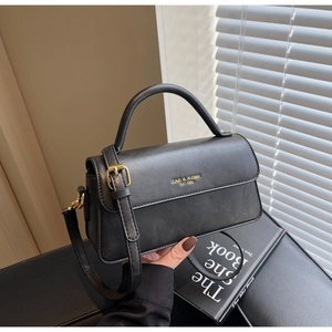 Close-up of black matte leather mini square bag with golden logo and adjustable strap