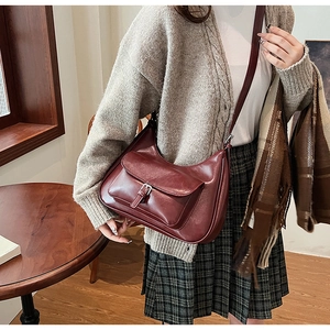 Macro detail of wine red crescent shoulder bag with vintage buckle on the front pocket