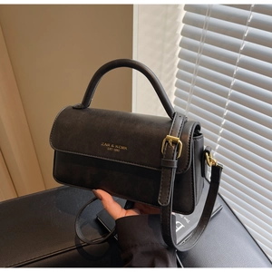 Close-up of black crossbody bag with gold brand logo and elegant top handle detail