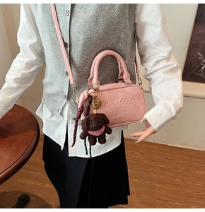 Detail of pink small square handbag with textured leather and cute puppy charm accessory