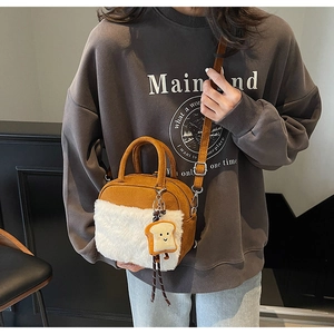 Detail of caramel suede crossbody bag with soft white plush panels and a toast charm