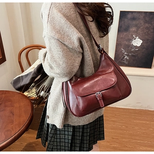 Retro burgundy leather crescent underarm bag with metal buckle on a shoulder strap
