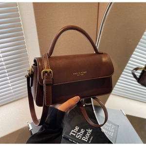 Detail of vintage brown leather crossbody bag with gold logo and flip-top closure