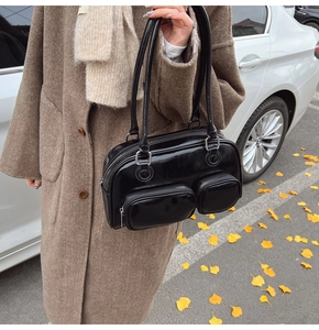 Dettaglio della borsa Boston in pelle verniciata nera con due tasche frontali con zip