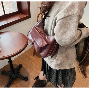 Detail view of burgundy underarm bag showing vintage clasp pocket and matte leather texture