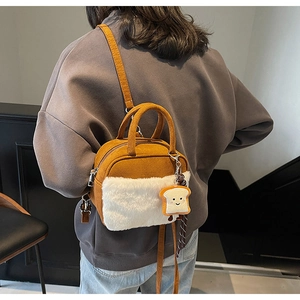 Detail of plush crossbody bag with furry white panel and toast-shaped charm on shoulder