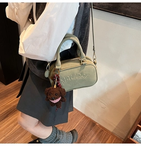 Close-up of a light green crossbody bag with a cute brown teddy bear plush charm