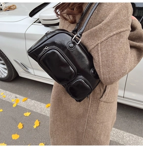 Dettaglio della borsa a spalla nera lucida con doppie tasche a zip e anelli d'argento