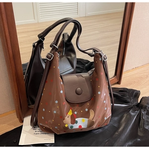 Detail of brown leather tote with polka dots and cute puppy embroidery and flap closure