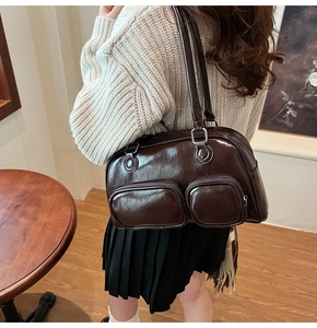 Dettaglio borsa a spalla marrone scuro in ecopelle con doppie tasche a zip e finitura lucida