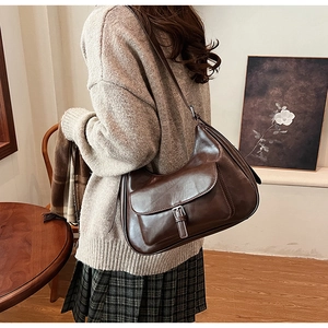 Detail of vintage brown shoulder bag with metal buckle and glossy synthetic leather finish