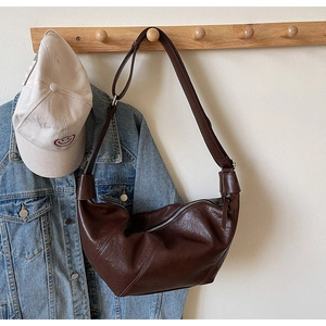 Detail of soft dark brown leather hobo bag with natural folds and top zipper closure