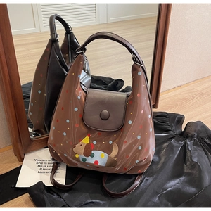 Detail of a brown polka dot backpack with a cute dog embroidery and a flap closure