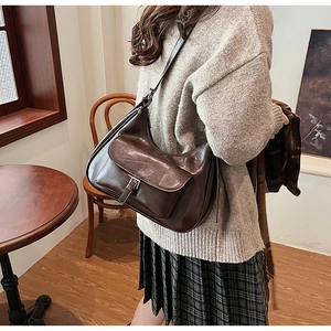 Brown vintage underarm bag worn with beige sweater in a cozy cafe setting