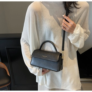 Detail of a vintage black leather crossbody bag with gold hardware and top handle