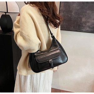 Detail of black leather underarm bag with vintage metal flap buckle on the front pocket