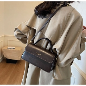 Close-up of retro dark brown leather handbag with gold lettering and sturdy top handle