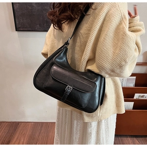Detail of a vintage black leather hobo bag with a silver buckle worn by a model