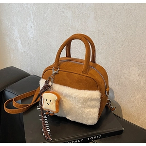 Detail of brown faux suede handbag with white faux fur trim and cute toast plush charm