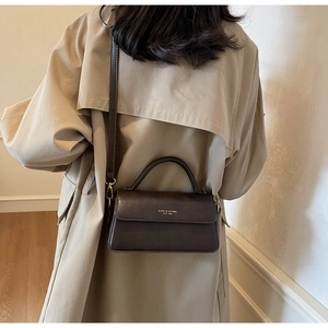 Model back view wearing brown vintage leather crossbody bag with khaki trench coat