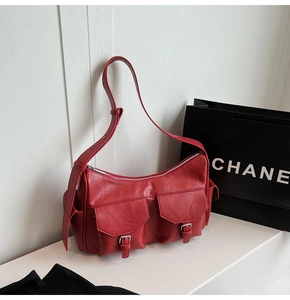 Detailed close-up of red textured PU leather shoulder bag with double buckle pockets