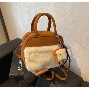Close-up of brown suede handbag with white faux fur panel and cute toast charm detail