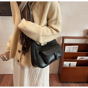 Detail of a vintage black leather shoulder bag with a functional front flap pocket and buckle