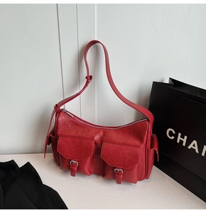 Macro detail of red vintage faux leather shoulder bag with buckle pockets and zipper