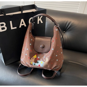 Detail of brown hobo bag with colorful dots and cute dog embroidery on smooth faux leather