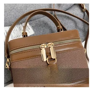 Detail of vintage brown bucket bag showing gold-toned zippers and leather top handle