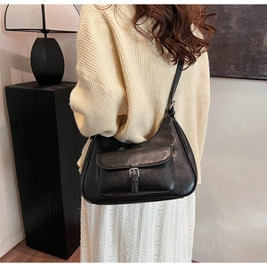 Detailed close-up of a black vintage leather underarm bag with silver metallic buckle detail