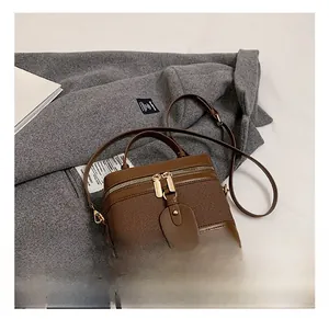 Detailed close-up of dark brown box-style handbag featuring canvas leather stitching