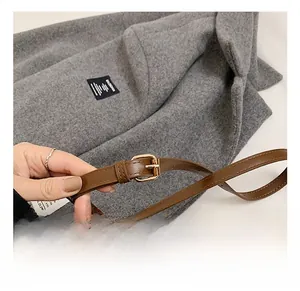 Close-up of adjustable brown leather strap with gold metal buckle on a bucket bag