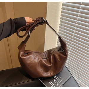 Close-up of dark brown vintage pleated leather dumpling bag with adjustable shoulder strap