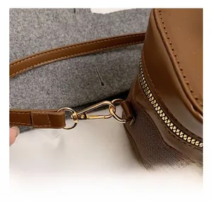 Detail of brown leather bucket bag showing golden metal hook and fine grid texture