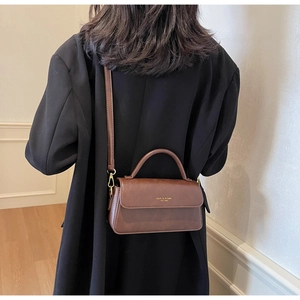 Brown leather crossbody bag shown on model highlighting compact size and stylish fit